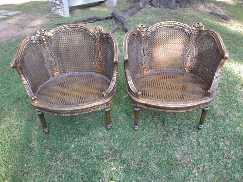 A French Louis XVI Style Pair of Ornately Carved Giltwood Rattan Bergere Chairs