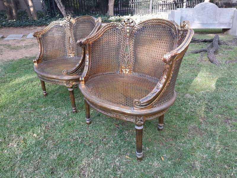 A French Louis XVI Style Pair of Ornately Carved Giltwood Rattan Bergere Chairs