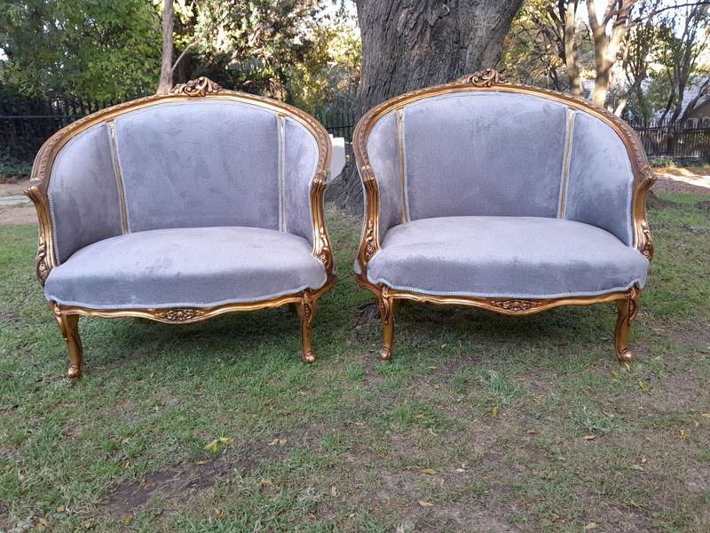A Pair of French Ornately Carved and Gilded Bergere Chairs