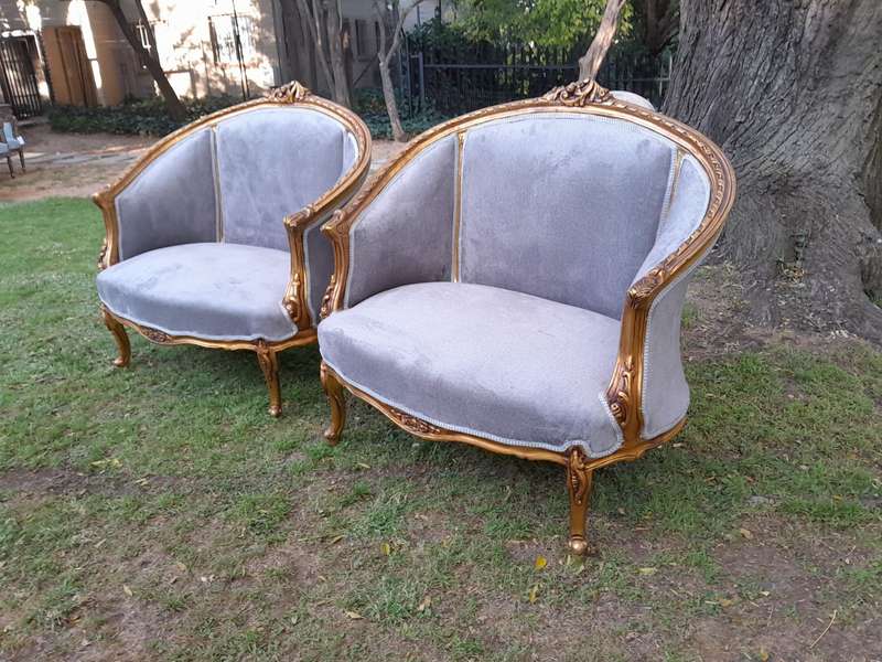 A Pair of French Ornately Carved and Gilded Bergere Chairs