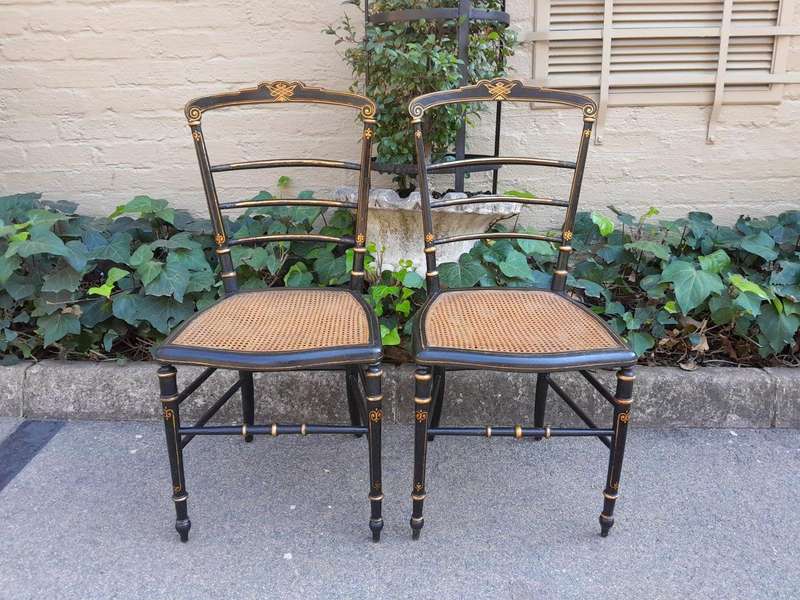 A Late 19th Century Circa 1880s Pair Of Victorian Ebonised And Gilt Painted Wooden Rattan Chairs