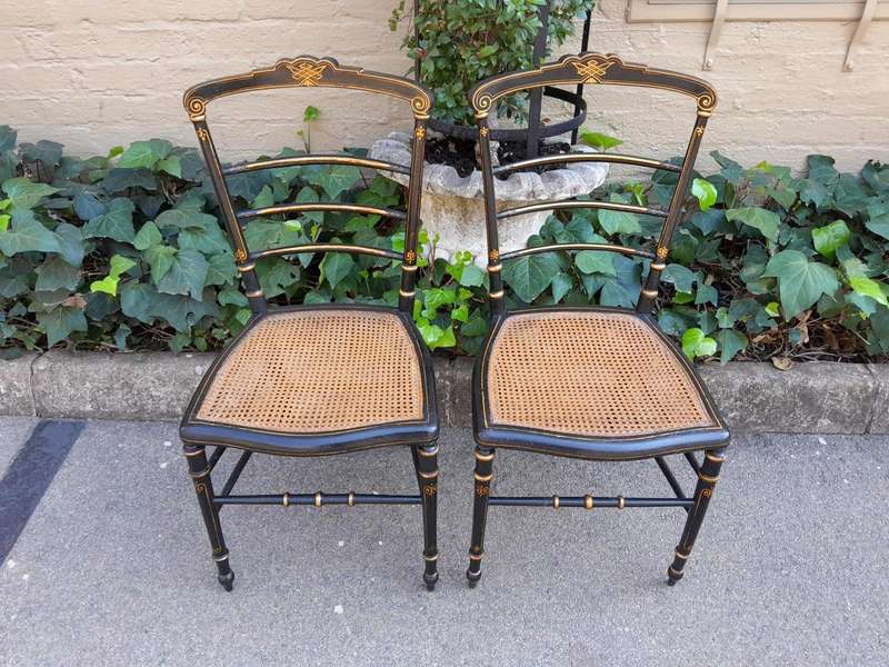 A Late 19th Century Circa 1880s Pair Of Victorian Ebonised And Gilt Painted Wooden Rattan Chairs
