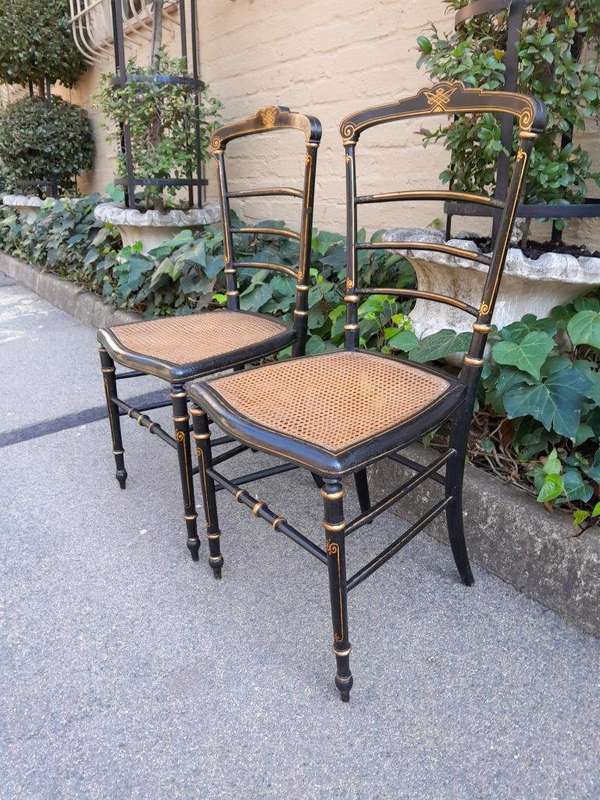 A Late 19th Century Circa 1880s Pair Of Victorian Ebonised And Gilt Painted Wooden Rattan Chairs