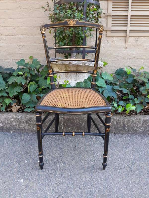 A Late 19th Century Circa 1880s Pair Of Victorian Ebonised And Gilt Painted Wooden Rattan Chairs