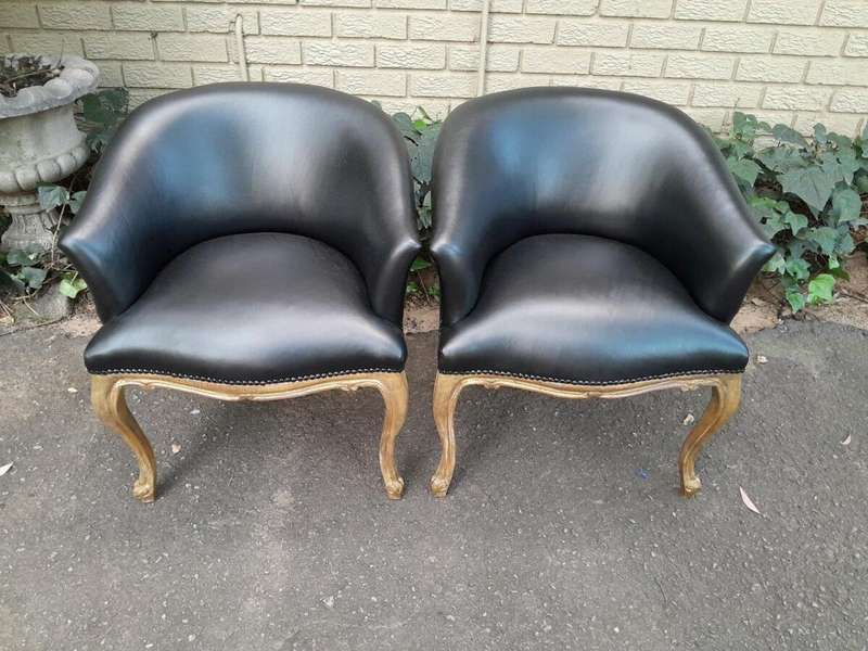 A French Style Pair of Carved Wooden and Hand-Gilded Tub Chairs Upholstered in Black Leather