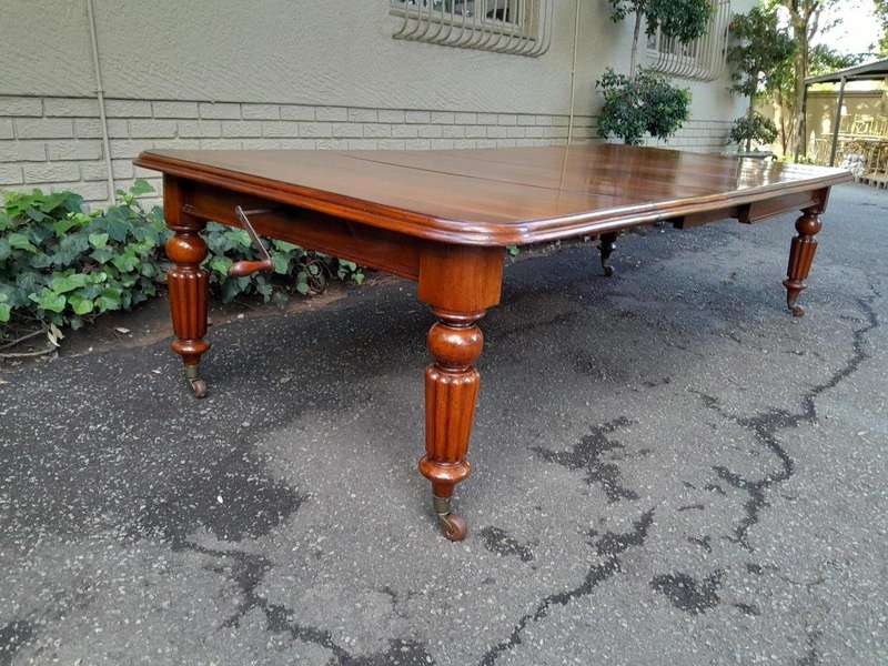 An Antique Edwardian Extending Dining Table with Heavily Carved Legs on Castors and with Crank Ha...