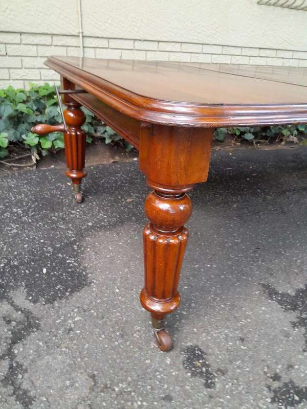 An Antique Edwardian Extending Dining Table with Heavily Carved Legs on Castors and with Crank Ha...