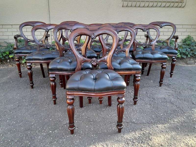 A 20th Century Set Of Twelve Teak Wood Bustle Back Chairs Comprising A Pair Of Carvers / Armchair...