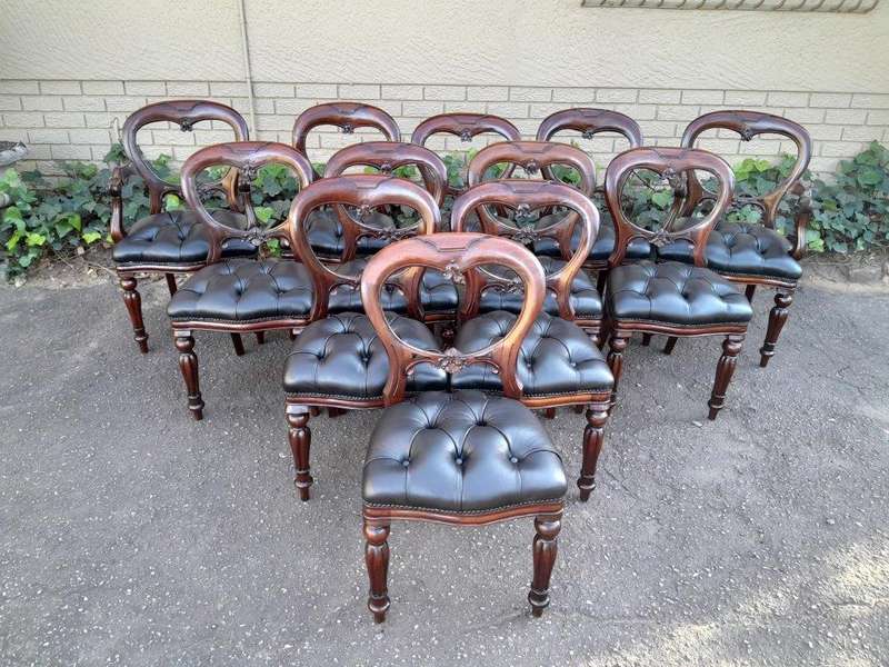 A 20th Century Set Of Twelve Teak Wood Bustle Back Chairs Comprising A Pair Of Carvers / Armchair...