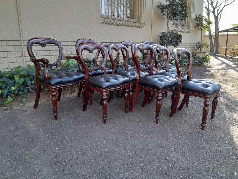 A 20th Century Set Of Twelve Teak Wood Bustle Back Chairs Comprising A Pair Of Carvers / Armchair...