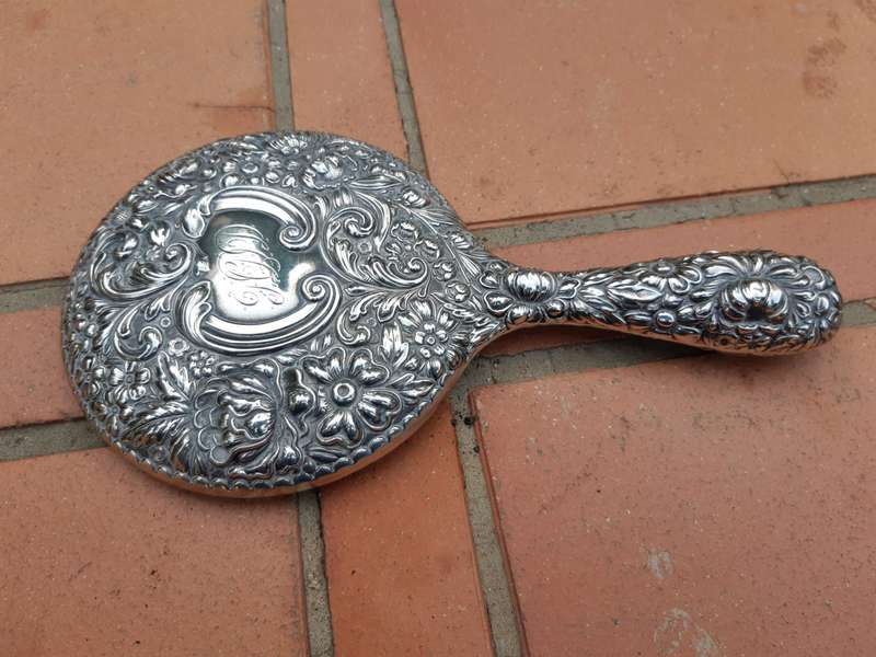 An Antique Repoussé Sterling Silver Hand Held Mirror with signed initials "HDD"