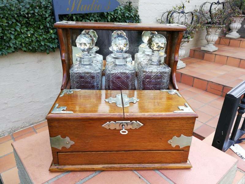 An Oak Tantalus With Silver Plate Fittings And Three Decanters With Key And Secret Drawer ND