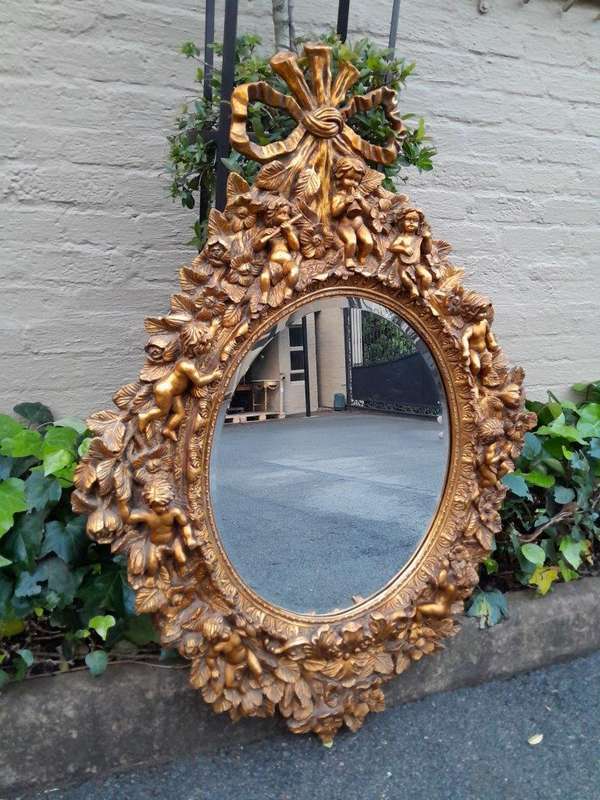A 20th Century Baroque Style Heavily Carved And Ornate Gilt-Framed Bevelled Glass Mirror