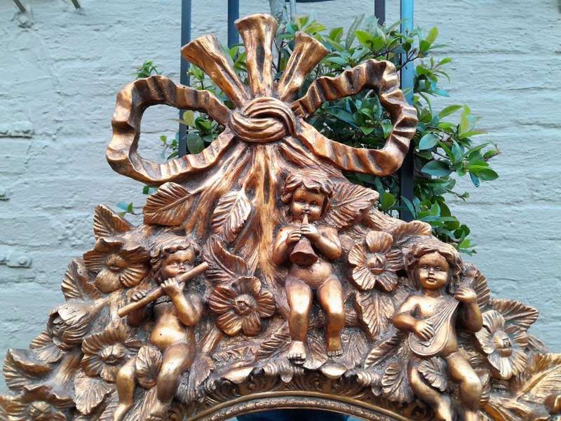 A 20th Century Baroque Style Heavily Carved And Ornate Gilt-Framed Bevelled Glass Mirror