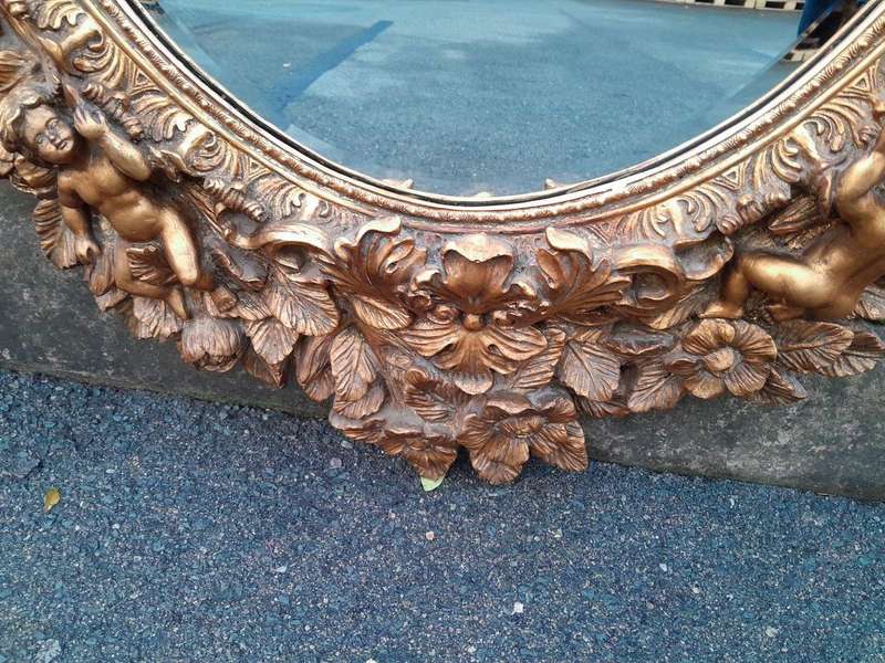 A 20th Century Baroque Style Heavily Carved And Ornate Gilt-Framed Bevelled Glass Mirror