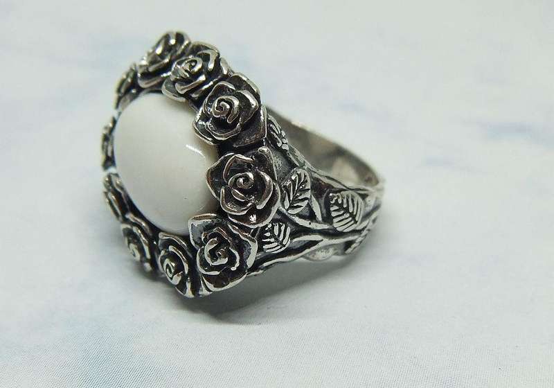 A STUNNING VINTAGE SOLID STERLING SILVER RING WITH WHITE CABOCHON STONE INSET AND ROSE DETAIL