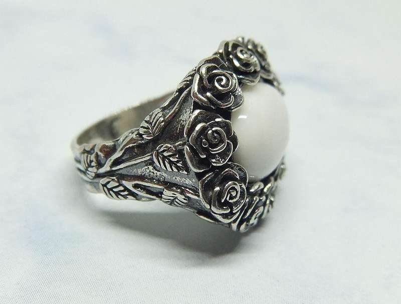 A STUNNING VINTAGE SOLID STERLING SILVER RING WITH WHITE CABOCHON STONE INSET AND ROSE DETAIL