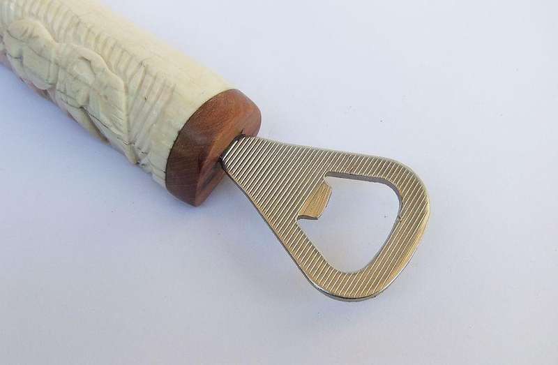 A UNIQUE VINTAGE CARVED BONE AND WOOD BOTTLE OPENER WITH ELEPHANT DETAIL - NEVER USED