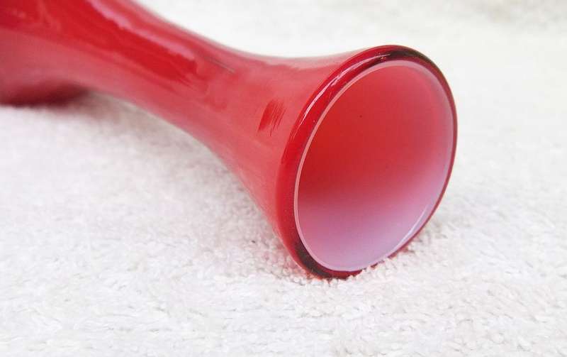 A STYLISH VINTAGE HAND BLOWN RED GLASS VASE WITH WHITE COLOURED INNER LINING