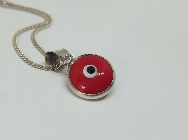 AN UNUSUAL STERLING SILVER AND RED GLASS EYE PENDANT WITH A STERLING SILVER NECKLACE !!
