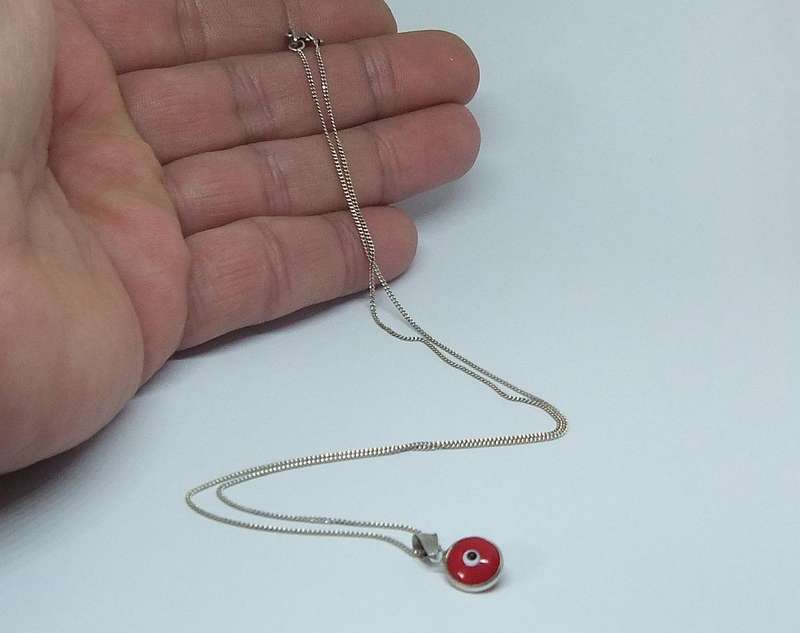 AN UNUSUAL STERLING SILVER AND RED GLASS EYE PENDANT WITH A STERLING SILVER NECKLACE !!