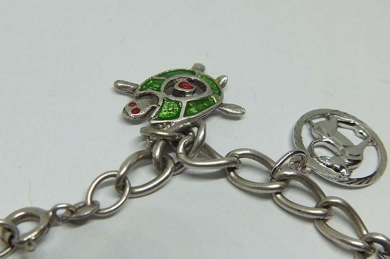 A VERY COOL VINTAGE STERLING SILVER CHARM BRACELET WITH VARIOUS DEGREES OF SILVER CHARMS , JUST LOOK