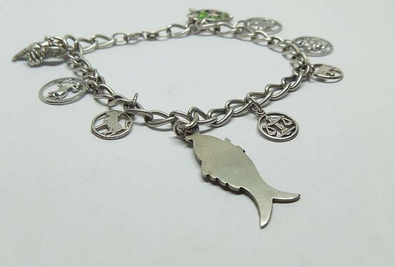 A VERY COOL VINTAGE STERLING SILVER CHARM BRACELET WITH VARIOUS DEGREES OF SILVER CHARMS , JUST LOOK