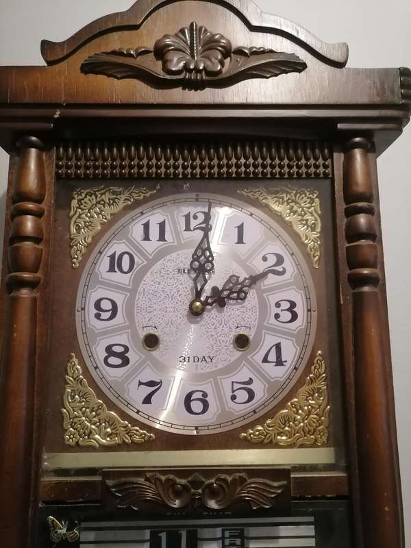 A vintage Blessing 31 day clock w/ day & date in a wood wall casing. Lifespace Sale - With Key