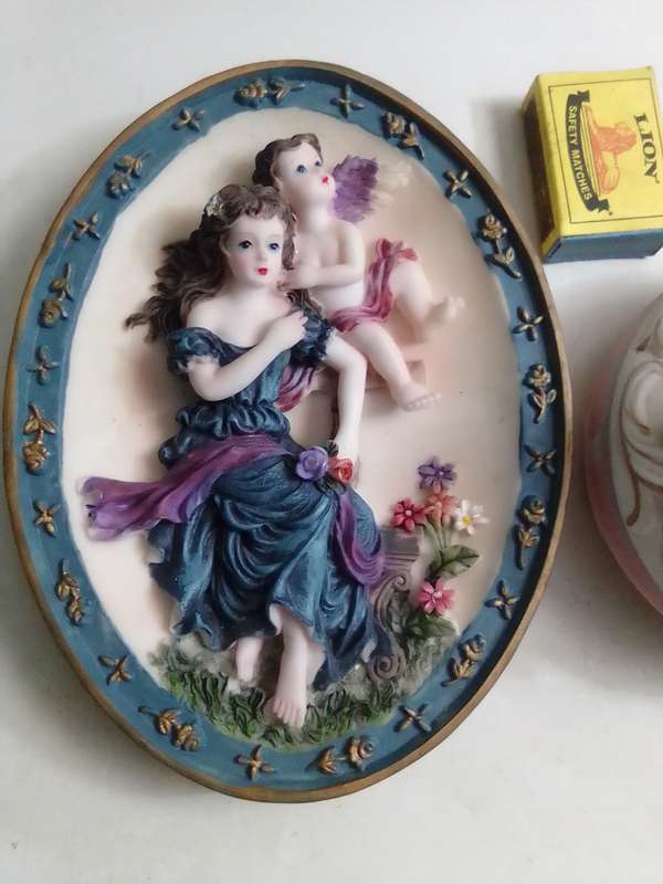 A Damsel and cherub Porcelain/polyresin wall plaque and a Cherub trinket lidded box.