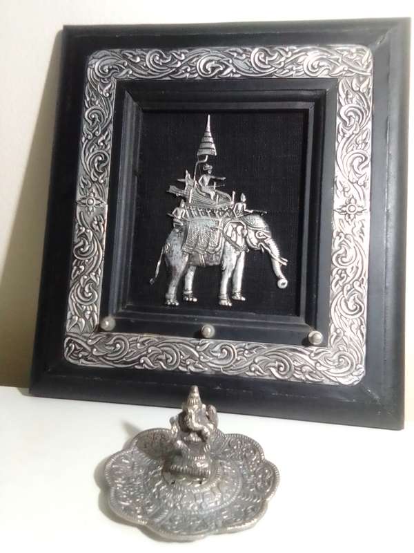 A white metal Incense burner holder and Radha Krishna on elephant on a wall hanging.