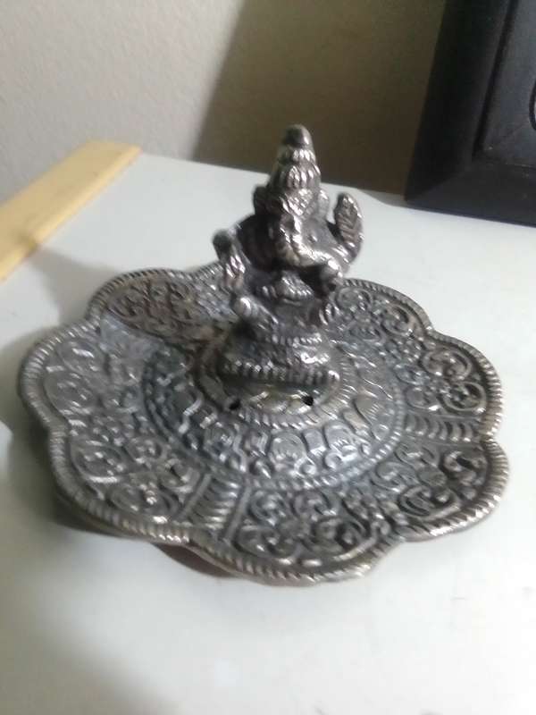A white metal Incense burner holder and Radha Krishna on elephant on a wall hanging.