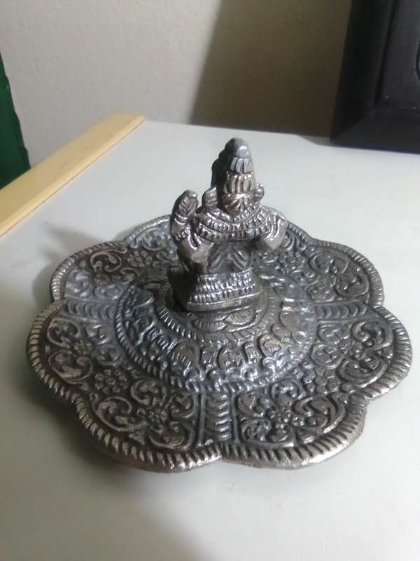 A white metal Incense burner holder and Radha Krishna on elephant on a wall hanging.