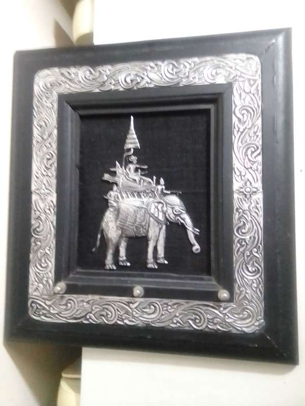 A white metal Incense burner holder and Radha Krishna on elephant on a wall hanging.