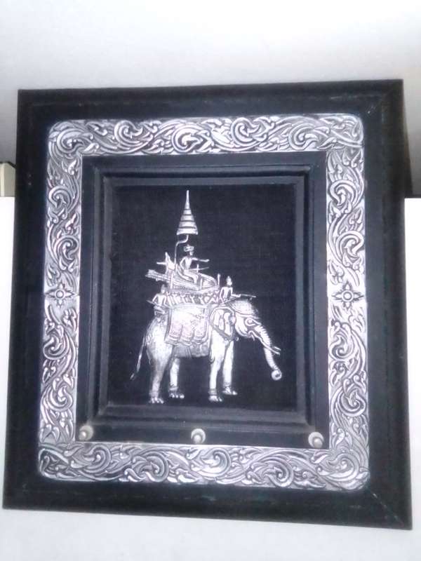 A white metal Incense burner holder and Radha Krishna on elephant on a wall hanging.
