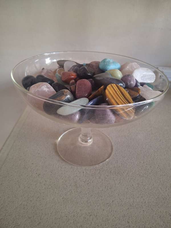 A glass bowl full of semi precious stones crystals