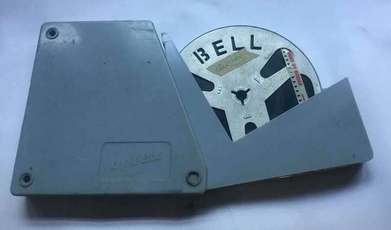 8 mm. BELL ALUMINIUM  FILM REEL , 120 mm. / 4 ins. diam. IN FLIP TOP ACRYLIC, OPTEX, CONTAINER