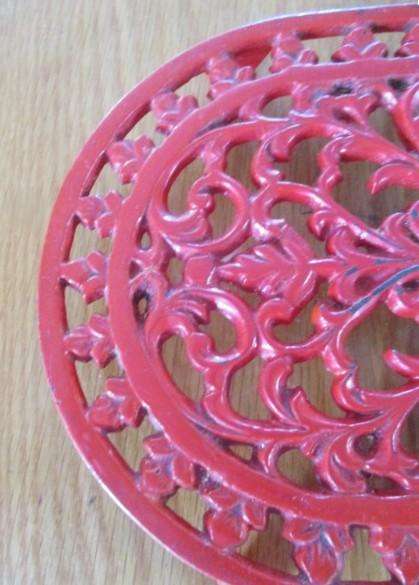 A heavy vintage cast iron trivet/pot stand with ornate floral and foliage design