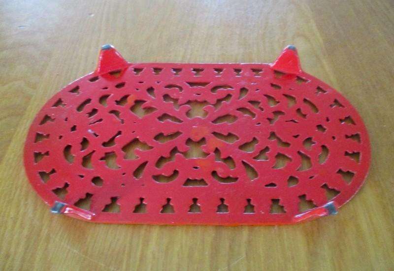 A heavy vintage cast iron trivet/pot stand with ornate floral and foliage design