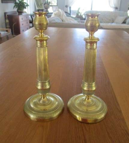 A pair of tall, decorative, etched brass candlesticks