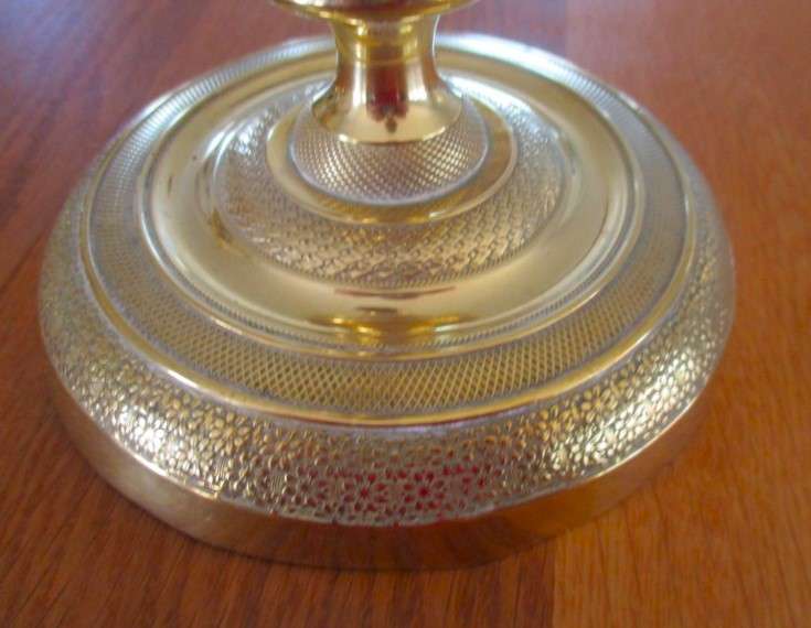 A pair of tall, decorative, etched brass candlesticks