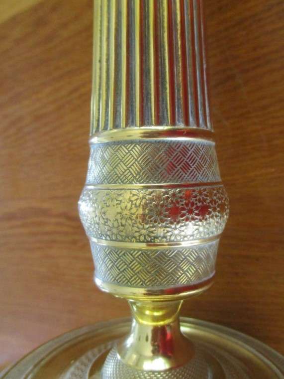 A pair of tall, decorative, etched brass candlesticks