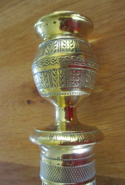 A pair of tall, decorative, etched brass candlesticks