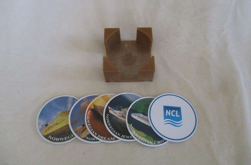 A set of six collectable metal NCL (Norwegian Cruise Lines) coasterss in holder