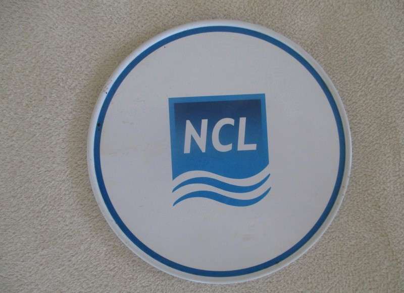 A set of six collectable metal NCL (Norwegian Cruise Lines) coasterss in holder