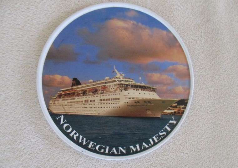 A set of six collectable metal NCL (Norwegian Cruise Lines) coasterss in holder