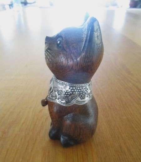 A cute small wooden cat with ornately engraved silver metal collar and inner ears
