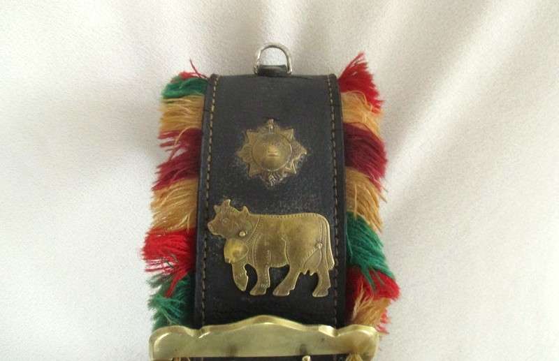 A very large vintage Swiss cow bell with ornate strap and buckle
