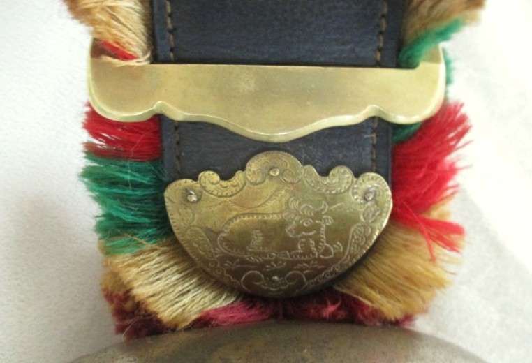 A very large vintage Swiss cow bell with ornate strap and buckle