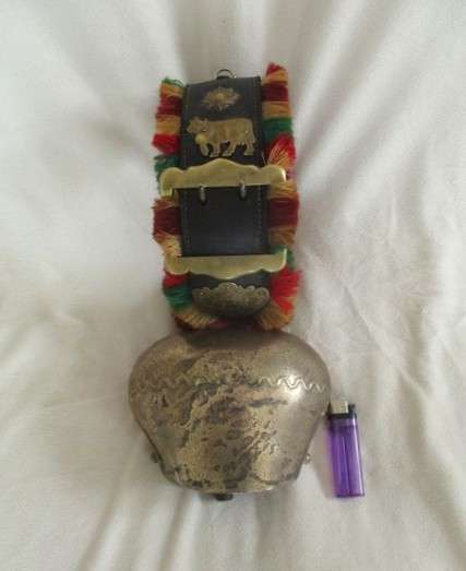 A very large vintage Swiss cow bell with ornate strap and buckle