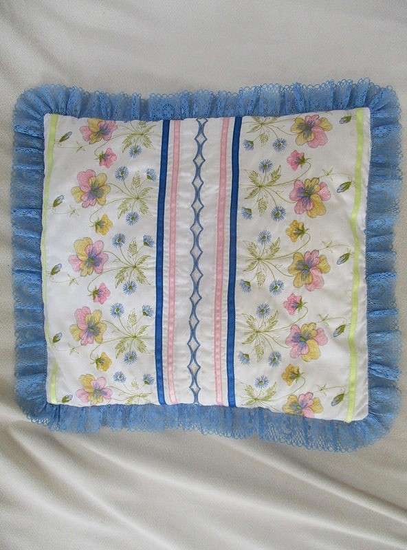A pretty cushion with dainty embroidery and lace border